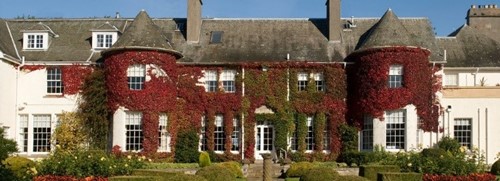 Rufflets St Andrews covered in deep red and green ivy under a clear blue autumn sky.