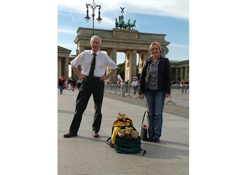 Couple standing near the Brandenburg Gate with backpacks full of teddy bears.
