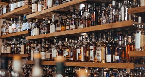 Shelves stacked with assorted whisky bottles in a warm, dimly lit bar.